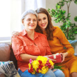 caregiver giving elder woman a gift and flower